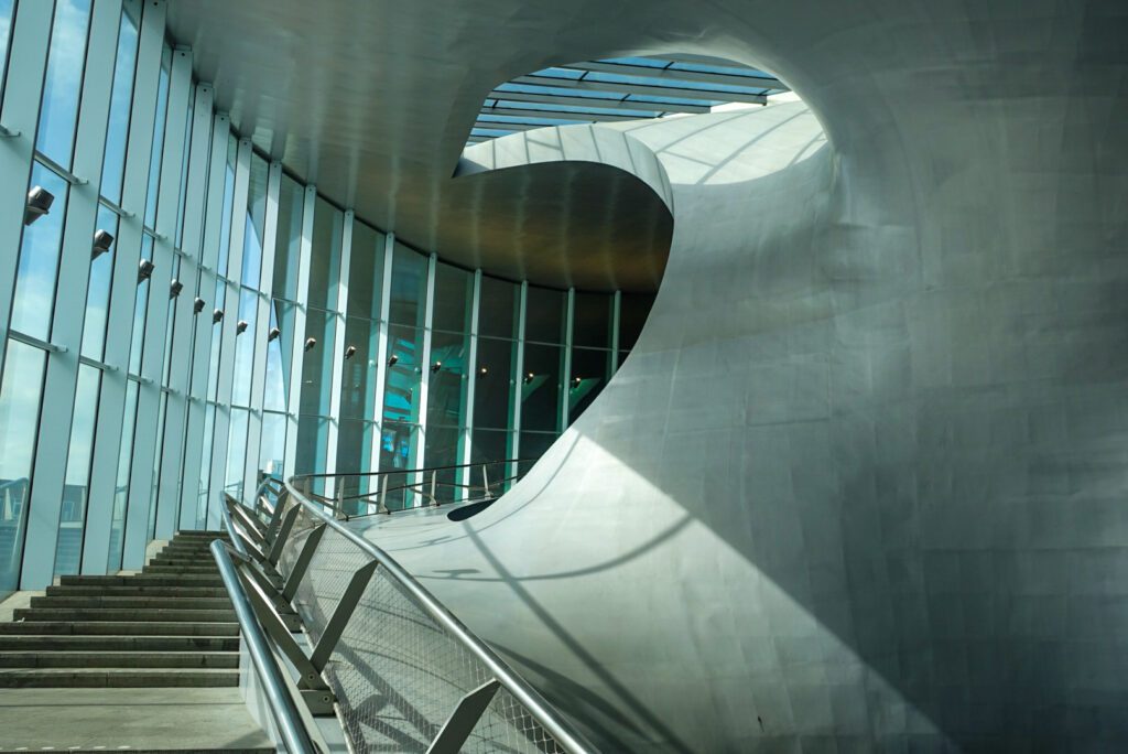 A picture of the curved concrete walls alongside glass windows of Arnhem train station. You can travel here directly from Düsseldorf with the Deutschlandticket