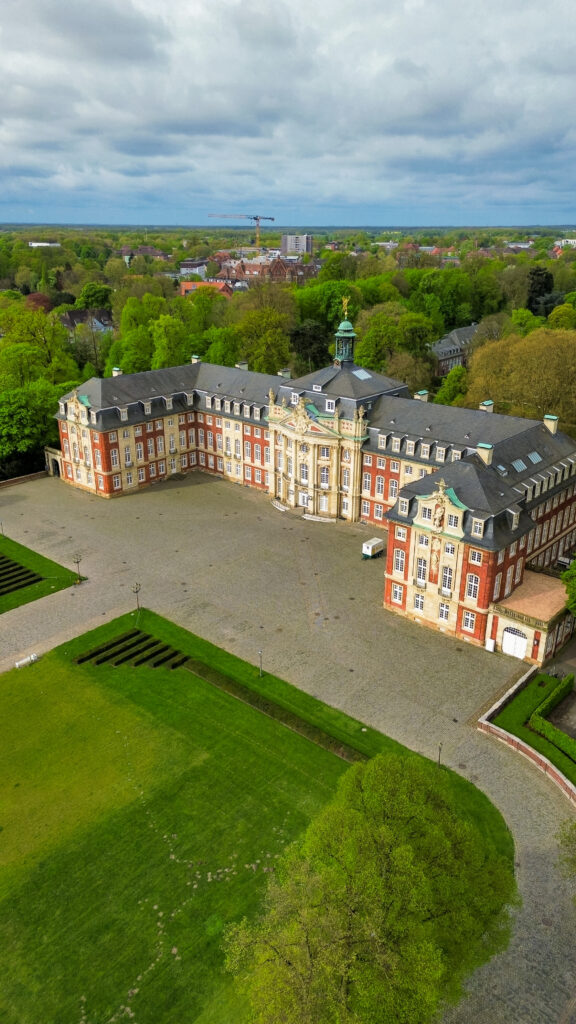 An aerial view of Schloss Münster, an 18th century Baroque castle at the Schlossplatz in Münster. Behind the Schloss you will find a botanical garden with free entry and multiple glass houses.