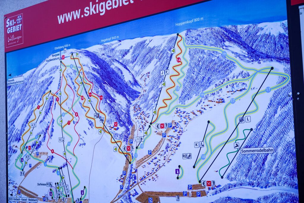 The ski map at Willingen details the connection between four different mountains in the village of Willingen in Upland. The mountains are connected, as shown on the plan, by blue and red pistes.