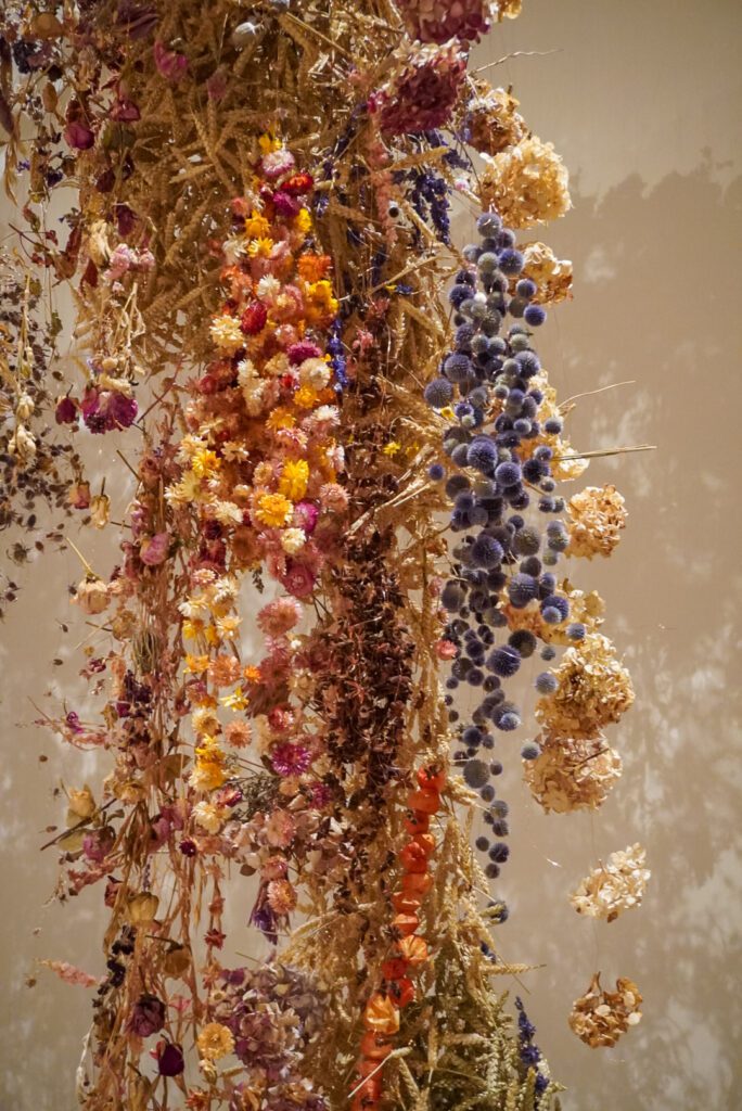 Dried flowers hang down from the ceiling of the Saatchi Gallery, There are over 100,000 flowers in total, coloured in gold, pink and purple.