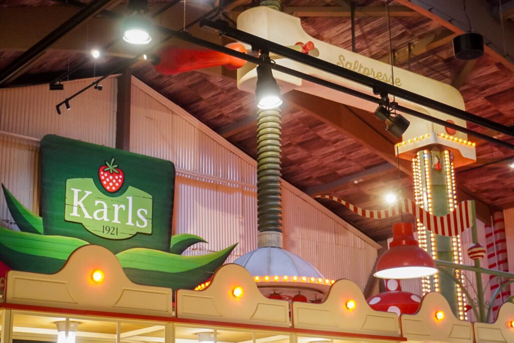 Karls Erlebnisdorf is a theme park located in Elstal near Berlin. One of the main attractions in the park is the Saftpresser, constructed out of two metal pillars, one of which is illuminated with LED lights. A green sign with the 'Karls' logo references to the park's logo.