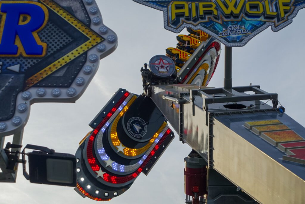 The "Airwolf" is a high-speed, inverting fairground ride at the SEND funfair. The ride is composed out of a central arm, with a silver-metallic theme, as well as two individual gondolas, which rotate on their own axis. They both have an intricate design with a yellow and red colour-scheme, as well as LED lights on the bottom of each of the cars.
