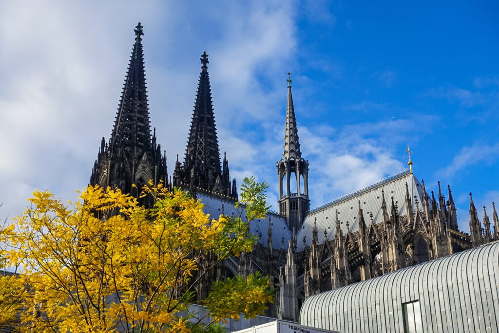 During the autumn season the Cologne Cathedral looks particularly impressive. The cathedral is surrounded by trees, the leaves of which turn into a yellow-golden-brown colour during the autumn season.